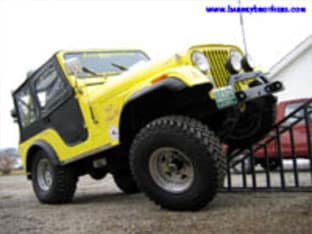Yellow off-road vehicle with a black soft top, parked on an incline, showcases customer rigs with a website URL visible in the top right corner.